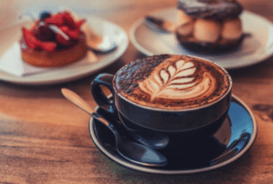Flat white coffee with leaf latte art served with pastries on a wooden table